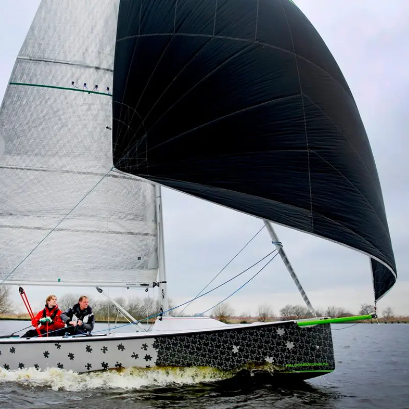 Segelboot Falcon Racing mit schwarzem Gennaker bei voller Fahrt auf dem Wasser