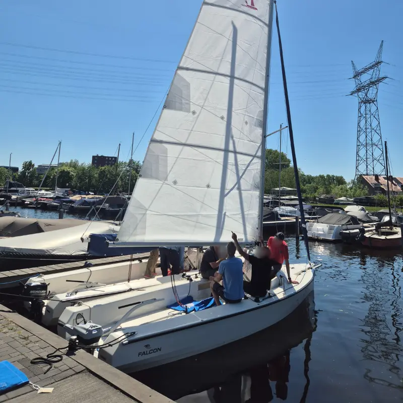 Segelboot Falcon mit gesetztem Großsegel und Außenborder im Hafen