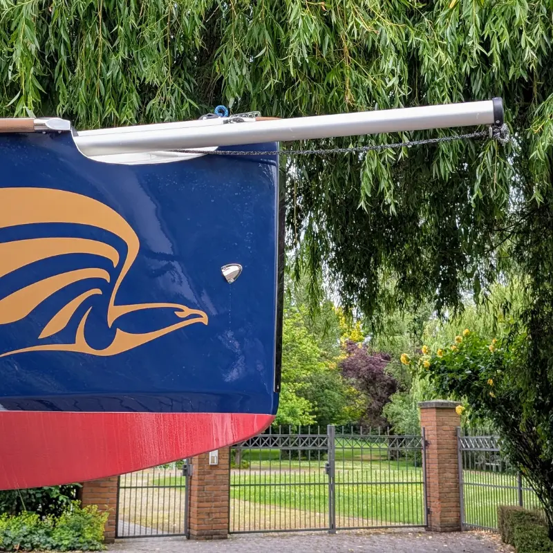 Ausgefahrener Gennakerbaum am Bug der Falcon Race mit goldfarbenem Logo